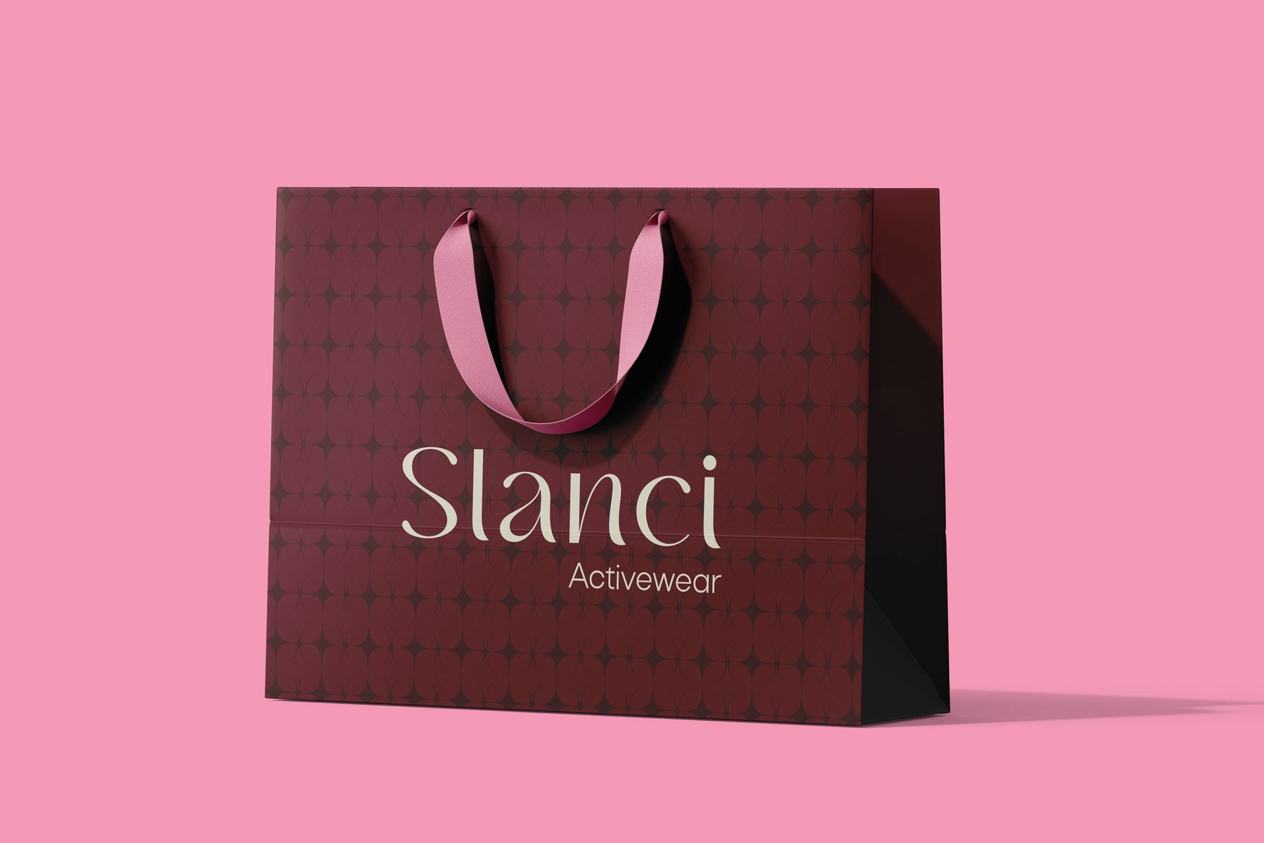 Sacola de papel bordô com padronagem de estrelas, alça de fita rosa e logo Slanci Activewear